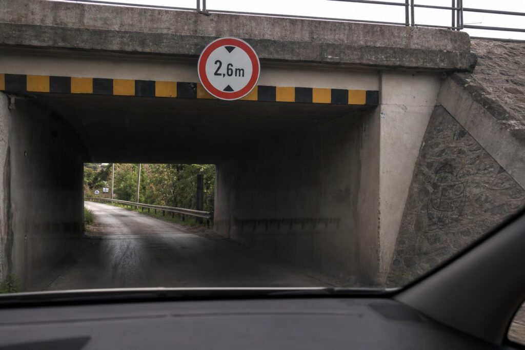 Magasságkorlátozó tábla egy alacsony aluljáró előtt, járműből nézve
