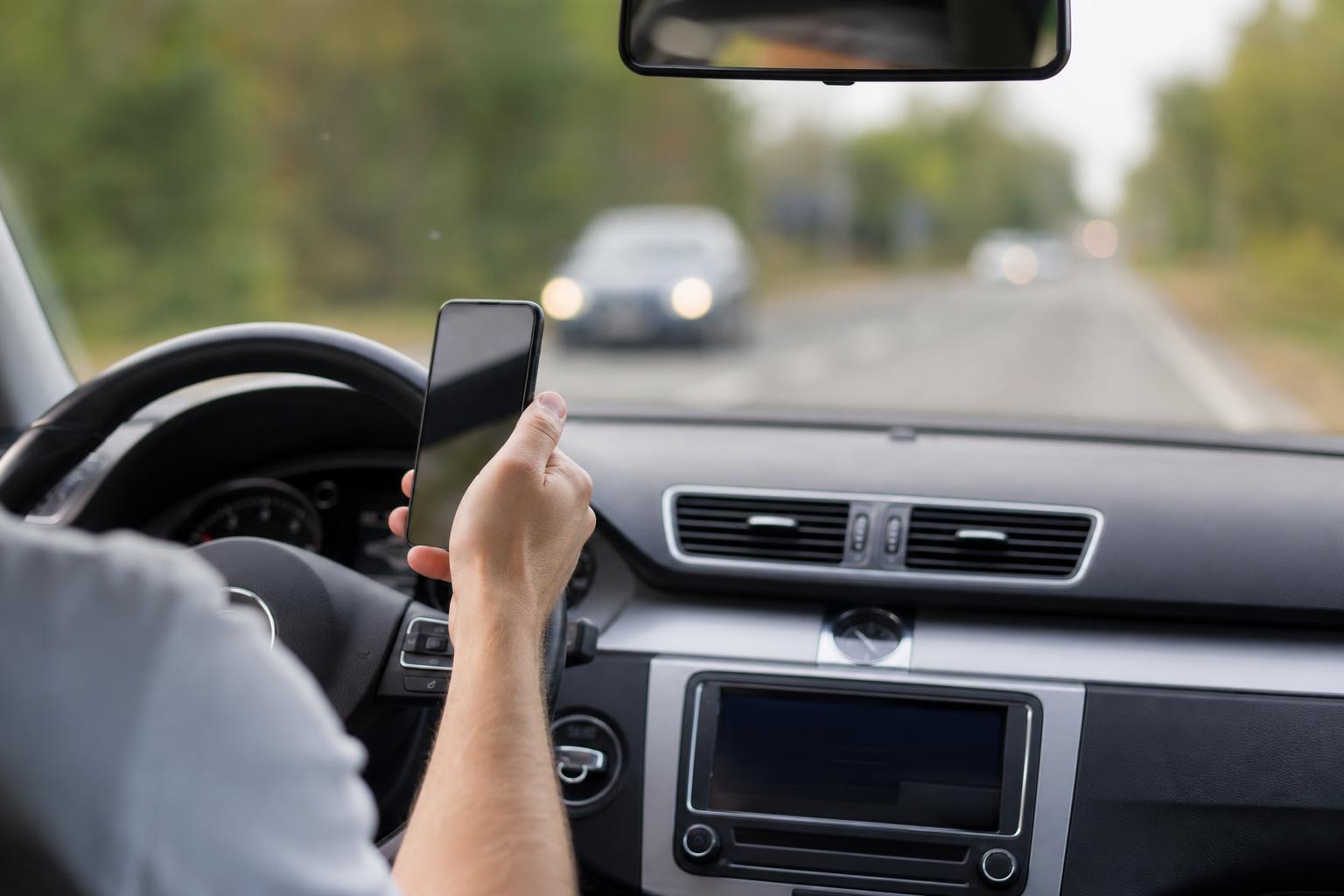 Vezetés közben kézben tartott telefonnal fényképező sofőr az autó utasterében