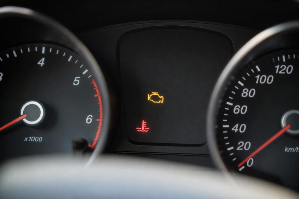 Autó műszerfala világító motorhiba- és hőmérséklet-visszajelzővel, amely a füstölő motor lehetséges hibájára utal