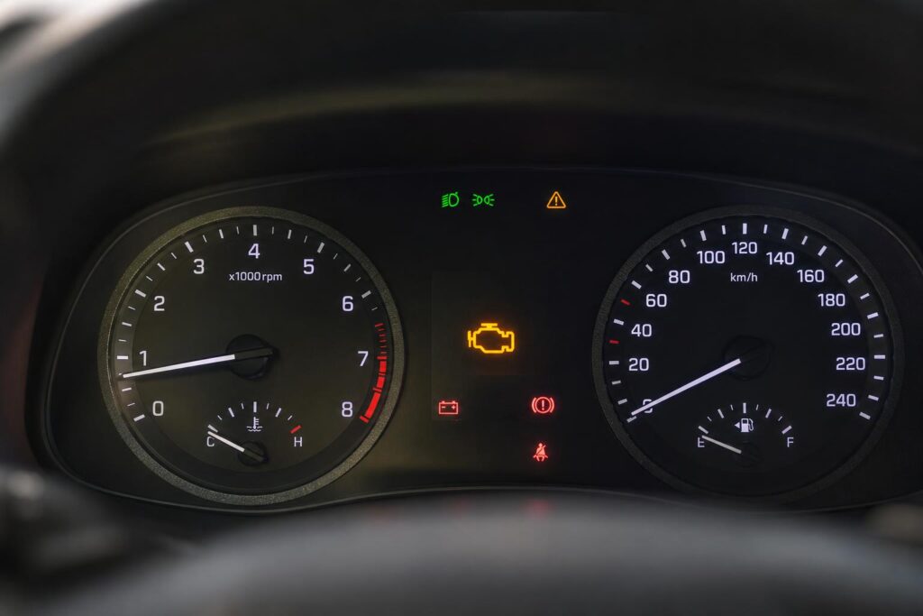 Autó műszerfalának közeli képe sikertelen indítás közben, világító motorhiba-jelző piktogrammal