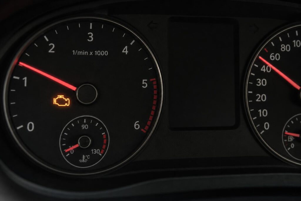 Autó műszerfala világító motorhiba-jelző ikonnal, gyorsításkor jelentkező motorvibráció témájához
