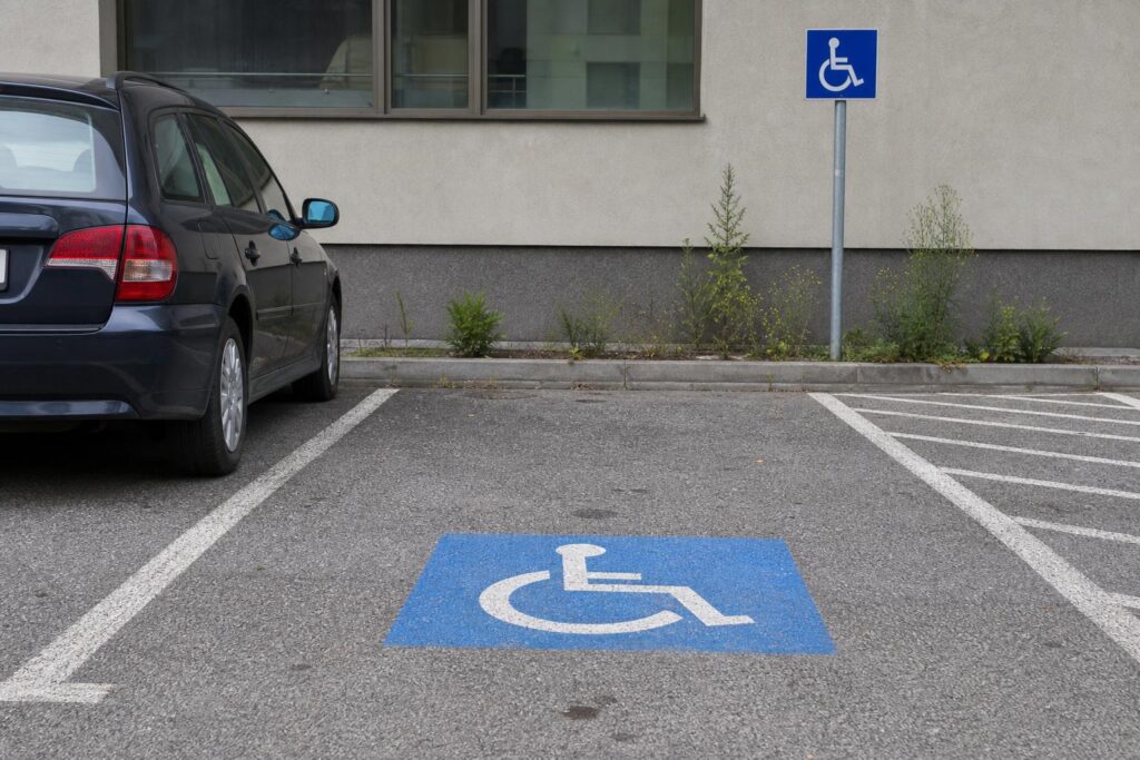 Mozgáskorlátozottak számára kijelölt parkolóhely kerekesszék-piktogrammal és parkolótáblával
