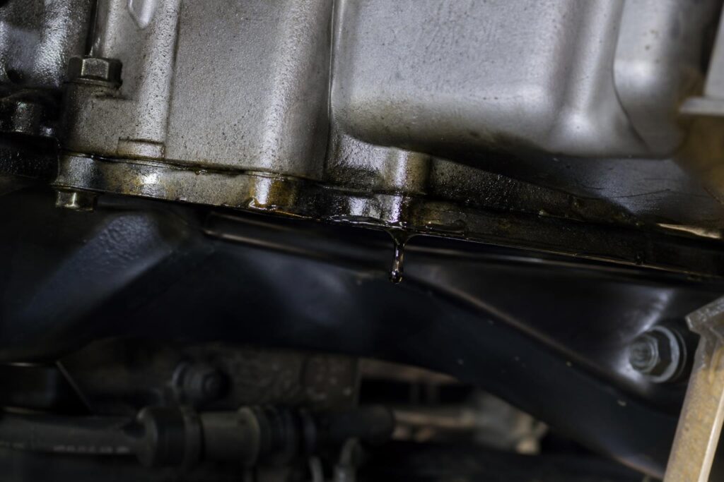 Friss motorolaj-szivárgás az autó motorjának alsó részén, az olajteknő tömítésénél