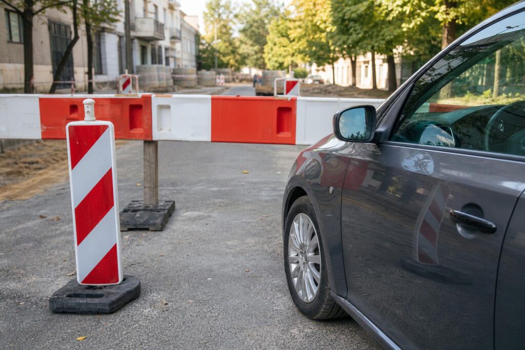 Személyautó ideiglenes útlezárás és terelőkorlát mögött, forgalom elől elzárt területen