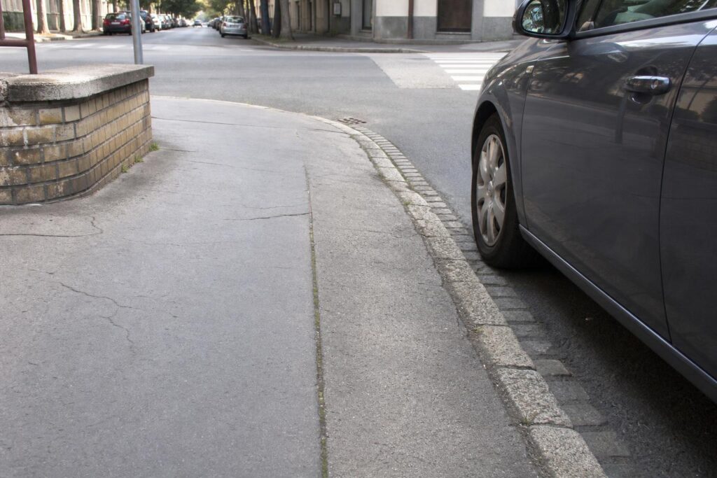 Autó a kereszteződéstől biztonságos távolságra, látható lekerekített járdaszegéllyel