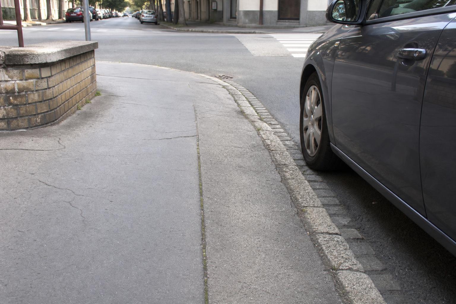 Autó a kereszteződéstől biztonságos távolságra, látható lekerekített járdaszegéllyel