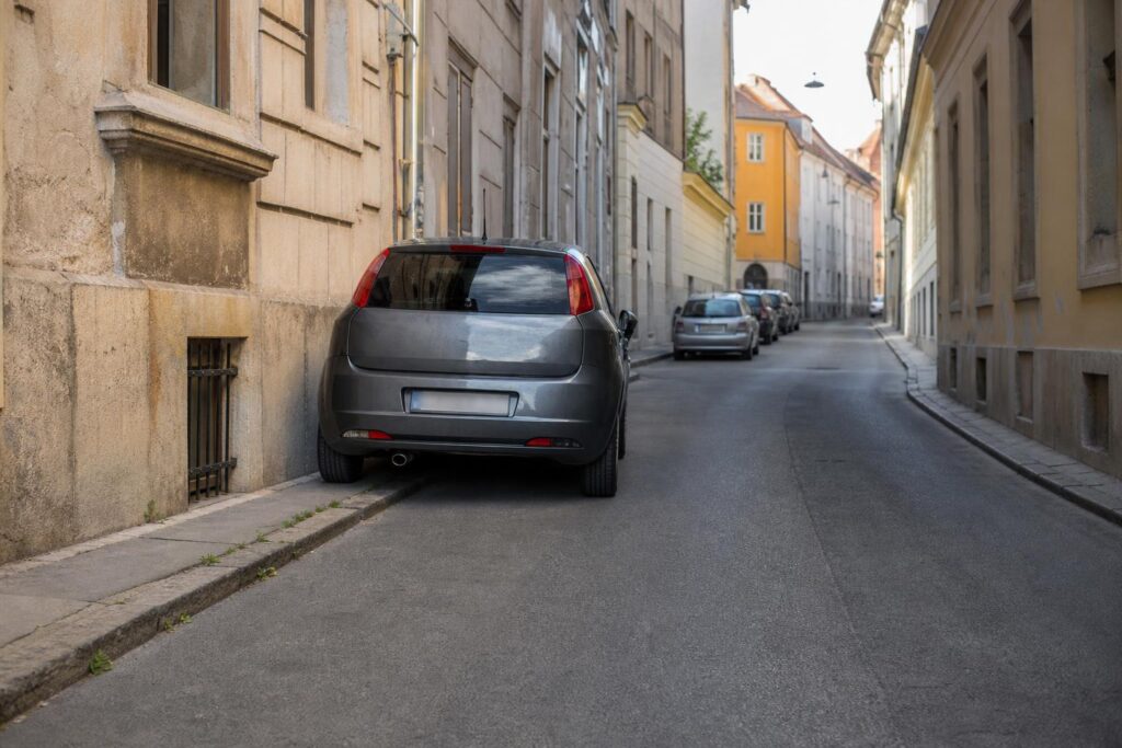 Szűk utcában szabályosan, az áthaladó forgalom számára elegendő helyet hagyva parkoló személyautó