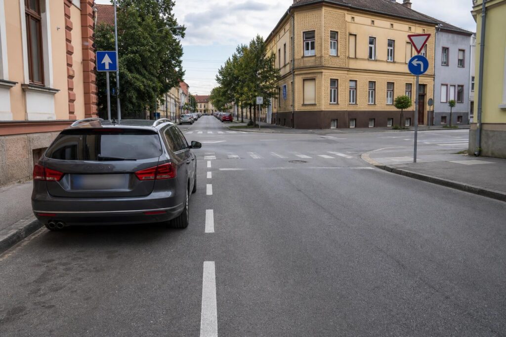 Autó parkolása útkereszteződéstől biztonságos távolságban, jól látható közúti jelzésekkel