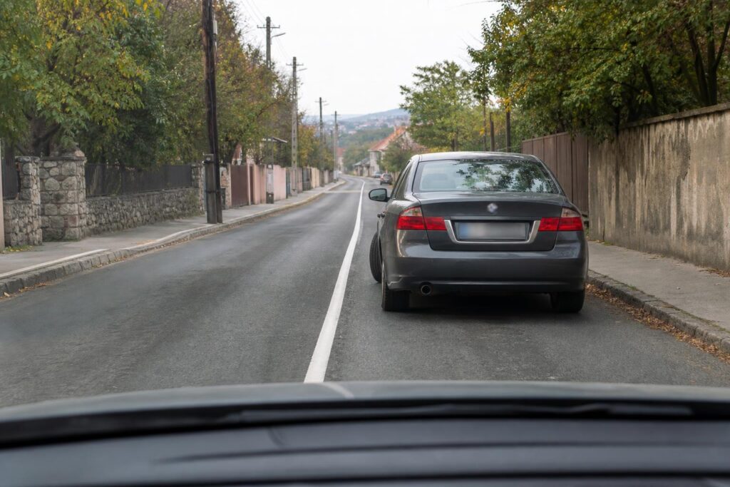Parkoló autó és záróvonal egy keskeny, korlátozottan belátható városi úton