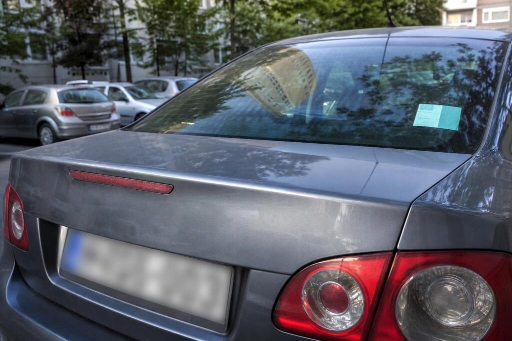 Parkoló autó régi engedélymatricával és felismerhetetlen rendszámmal városi parkolási zónában