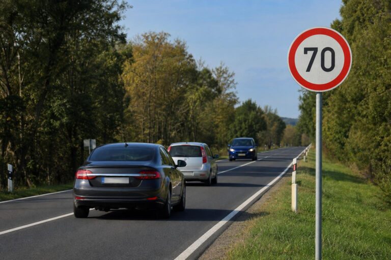 Személyautó szabályos előzése kétsávos országúton sebességkorlátozó táblával és szembejövő járművel