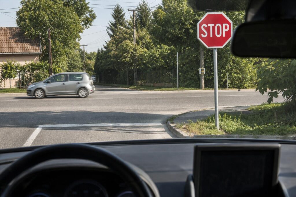 Autó közeledik STOP táblához és a felfestett stopvonalhoz egy kereszteződésben