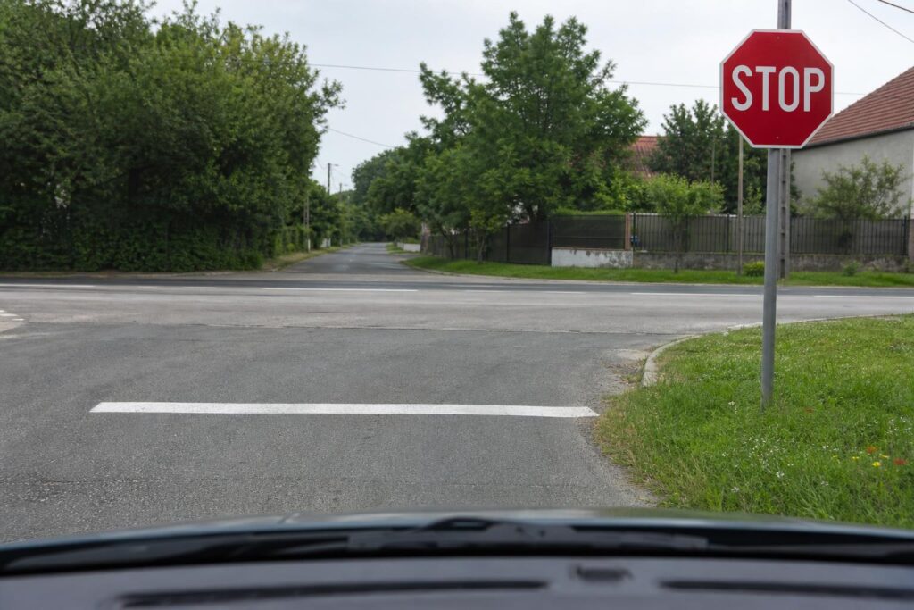 Autó a magyar STOP tábla előtti stopvonalnál egy útkereszteződésben