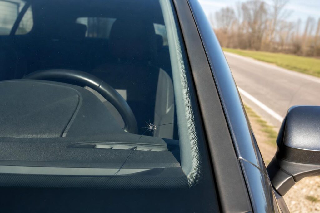 Kőfelverődés okozta csillag alakú sérülés és rövid repedés egy autó szélvédőjén