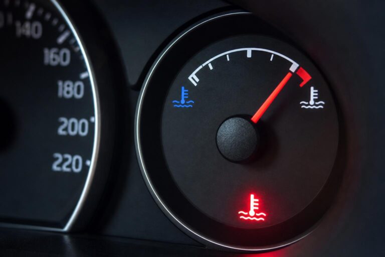 Autó műszerfala piros tartományba emelkedő motorhőmérséklet-jelzővel és gyári túlmelegedés-figyelmeztetéssel