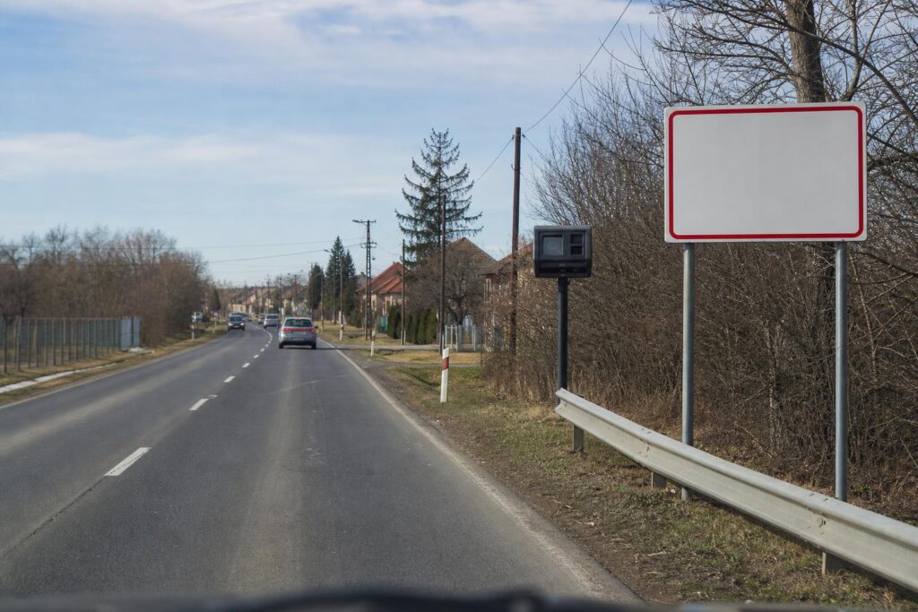 Lakott terület kezdetét jelző tábla és a közelében elhelyezett traffipax egy országúton