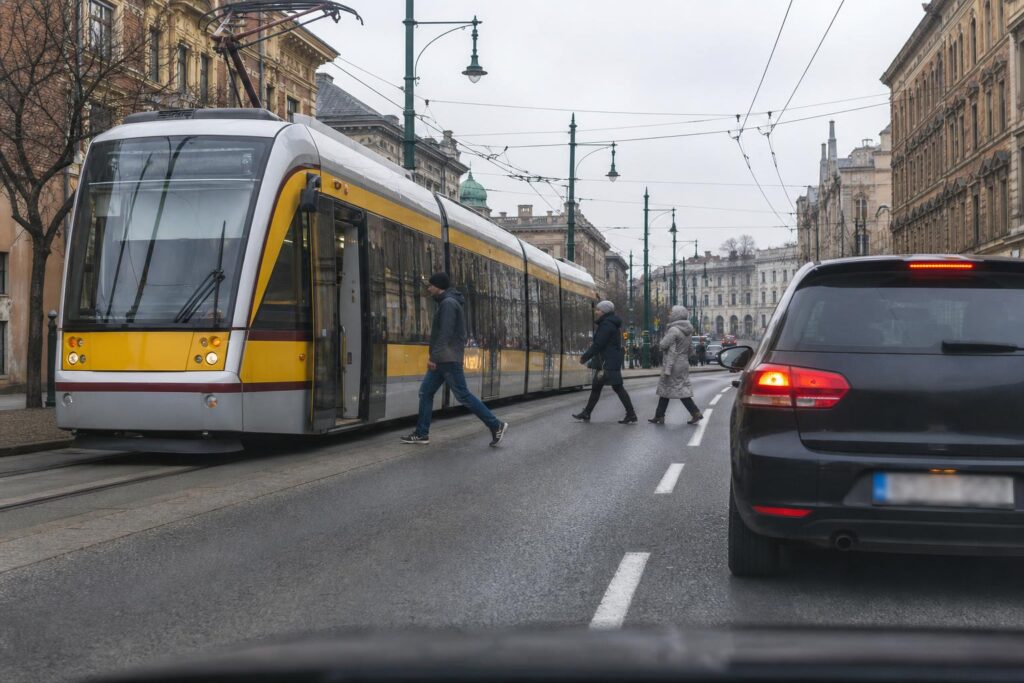 Megálló villamos és mögötte várakozó autó járdasziget nélküli útszakaszon