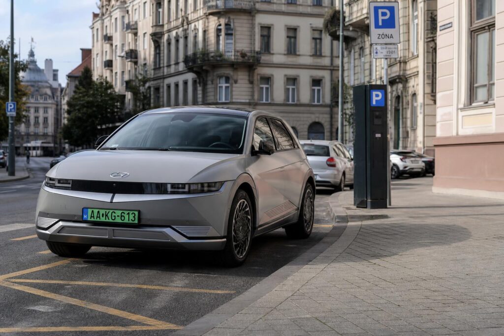 Zöld rendszámos villanyautó budapesti utcai parkolóhelyen