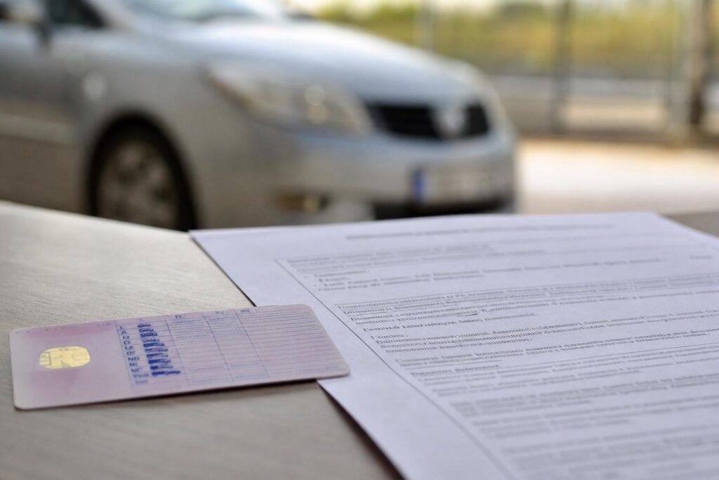 Vezetéstől eltiltásról szóló irat és jogosítvány egy autó mellett