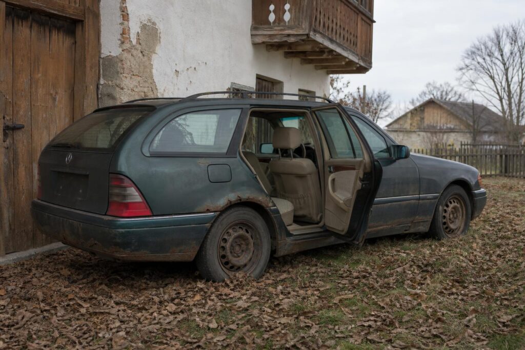 Rozsdás, egykori Mercedes C 230 Kompressor kombi egy alsó-ausztriai gazdaság mellett